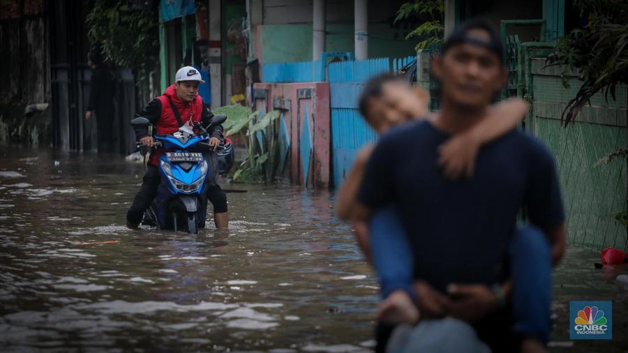 Warga melintas saat terjadi banjir pada pemukiman warga di kawasan Petogogan, Jakarta Selatan, Jumat (7/7/2023). (CNBC Indonesia/Faisal Rahman)