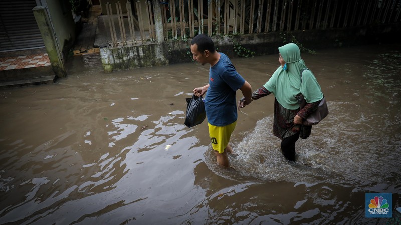 Warga melintas saat terjadi banjir pada pemukiman warga di kawasan Petogogan, Jakarta Selatan, Jumat (7/7/2023). (CNBC Indonesia/Faisal Rahman)