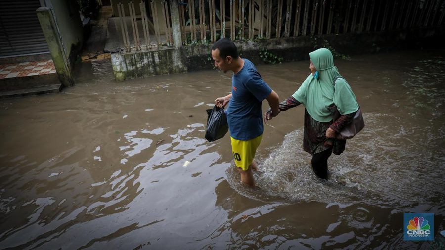Warga melintas saat terjadi banjir pada pemukiman warga di kawasan Petogogan, Jakarta Selatan, Jumat (7/7/2023). (CNBC Indonesia/Faisal Rahman)