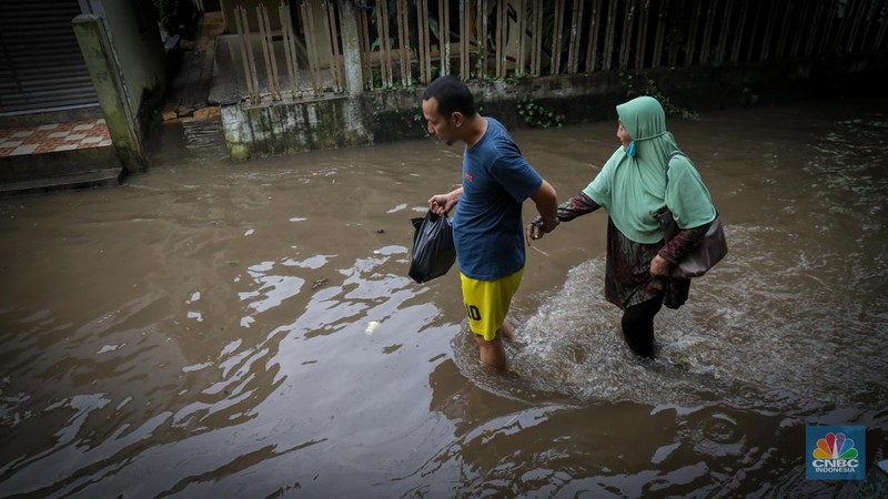 Warga melintas saat terjadi banjir pada pemukiman warga di kawasan Petogogan, Jakarta Selatan, Jumat (7/7/2023). (CNBC Indonesia/Faisal Rahman)