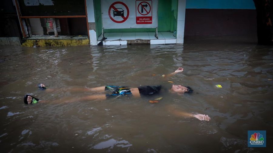 Warga melintas saat terjadi banjir pada pemukiman warga di kawasan Petogogan, Jakarta Selatan, Jumat (7/7/2023). (CNBC Indonesia/Faisal Rahman)