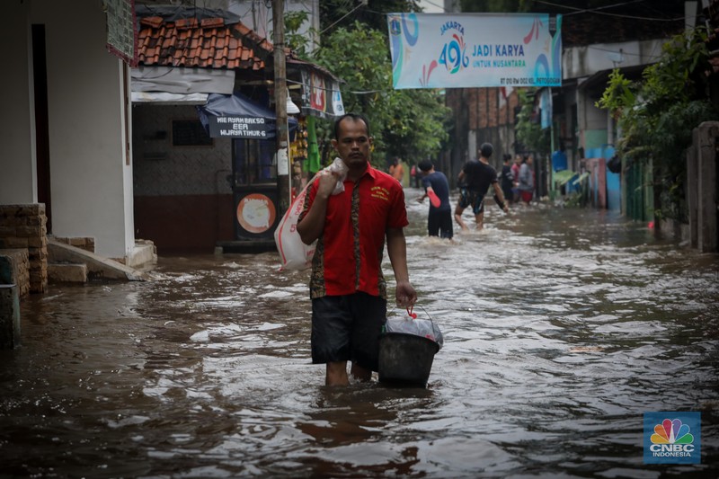Warga melintas saat terjadi banjir pada pemukiman warga di kawasan Petogogan, Jakarta Selatan, Jumat (7/7/2023). (CNBC Indonesia/Faisal Rahman)