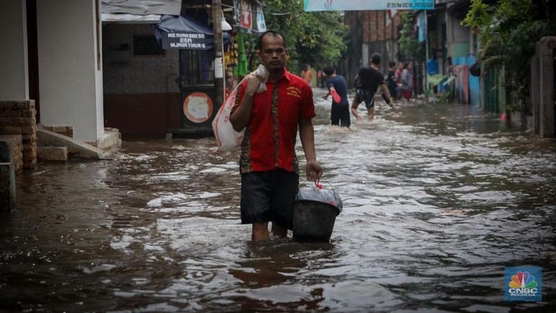 Warga melintas saat terjadi banjir pada pemukiman warga di kawasan Petogogan, Jakarta Selatan, Jumat (7/7/2023). (CNBC Indonesia/Faisal Rahman)