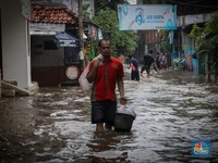 Warga melintas saat terjadi banjir pada pemukiman warga di kawasan Petogogan, Jakarta Selatan, Jumat (7/7/2023). (CNBC Indonesia/Faisal Rahman)