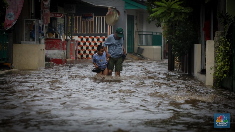 Warga melintas saat terjadi banjir pada pemukiman warga di kawasan Petogogan, Jakarta Selatan, Jumat (7/7/2023). (CNBC Indonesia/Faisal Rahman)