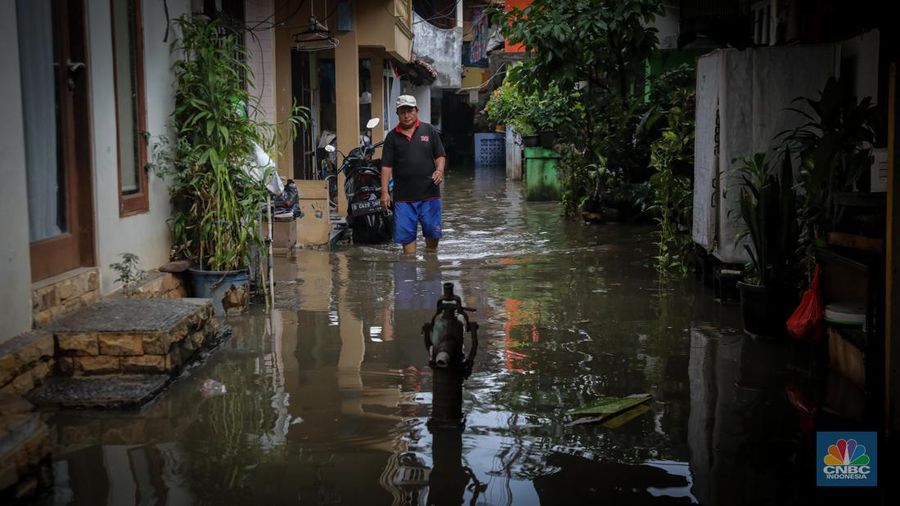 Warga melintas saat terjadi banjir pada pemukiman warga di kawasan Petogogan, Jakarta Selatan, Jumat (7/7/2023). (CNBC Indonesia/Faisal Rahman)