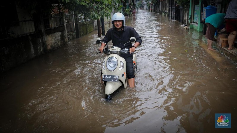 Warga melintas saat terjadi banjir pada pemukiman warga di kawasan Petogogan, Jakarta Selatan, Jumat (7/7/2023). (CNBC Indonesia/Faisal Rahman)