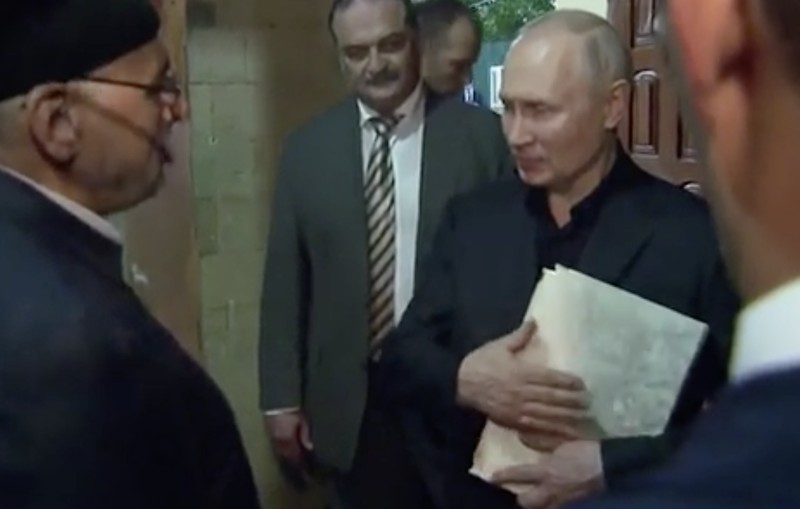 Presiden Rusia, Vladimir Putin pegang Al Qur'an. (Tangakapan Layar/REUTERS)