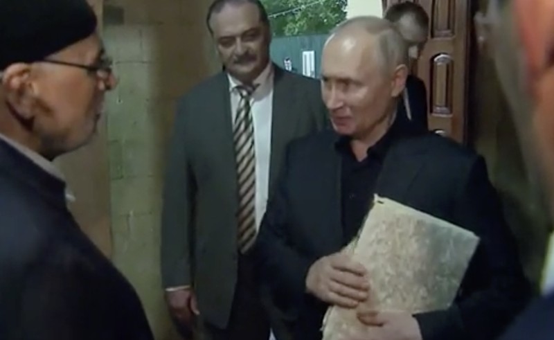 Presiden Rusia, Vladimir Putin pegang Al Qur'an. (Tangakapan Layar/REUTERS)