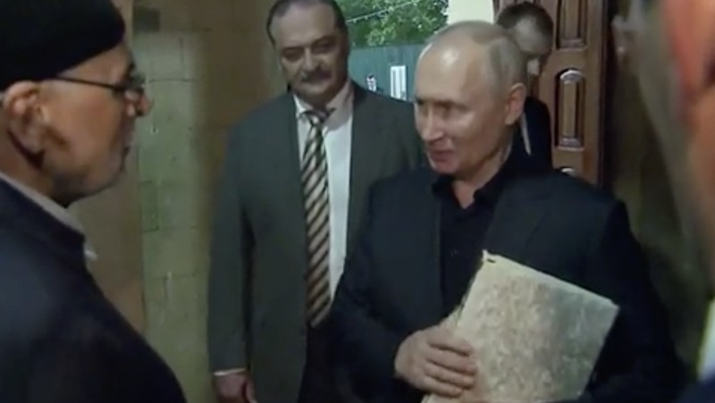 Presiden Rusia, Vladimir Putin pegang Al Qur'an. (Tangakapan Layar/REUTERS)