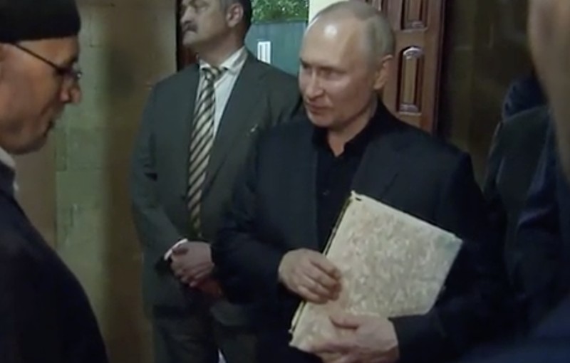 Presiden Rusia, Vladimir Putin pegang Al Qur'an. (Tangakapan Layar/REUTERS)
