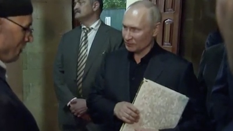 Presiden Rusia, Vladimir Putin pegang Al Qur'an. (Tangakapan Layar/REUTERS)