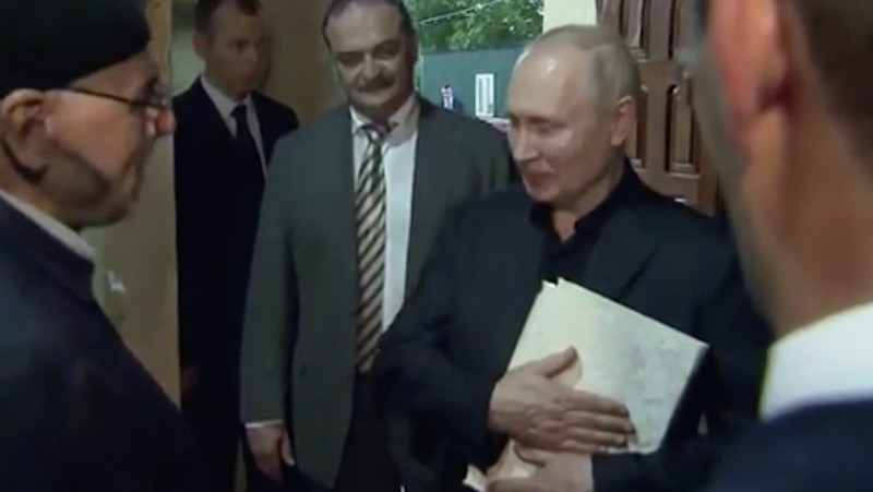Presiden Rusia, Vladimir Putin pegang Al Qur'an. (Tangakapan Layar/REUTERS)