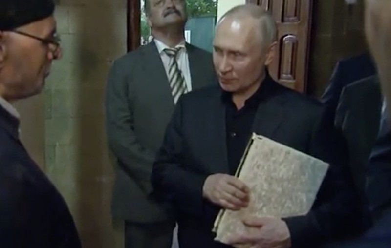 Presiden Rusia, Vladimir Putin pegang Al Qur'an. (Tangakapan Layar/REUTERS)