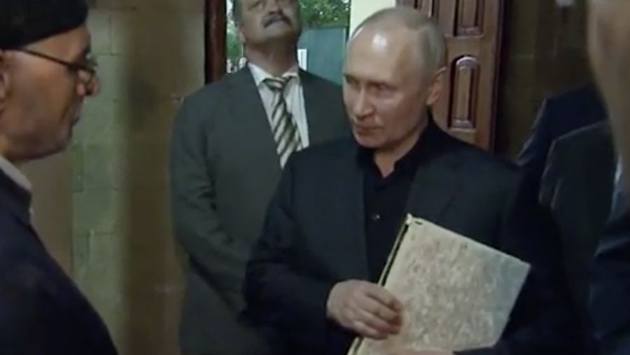 Presiden Rusia, Vladimir Putin pegang Al Qur'an. (Tangakapan Layar/REUTERS)