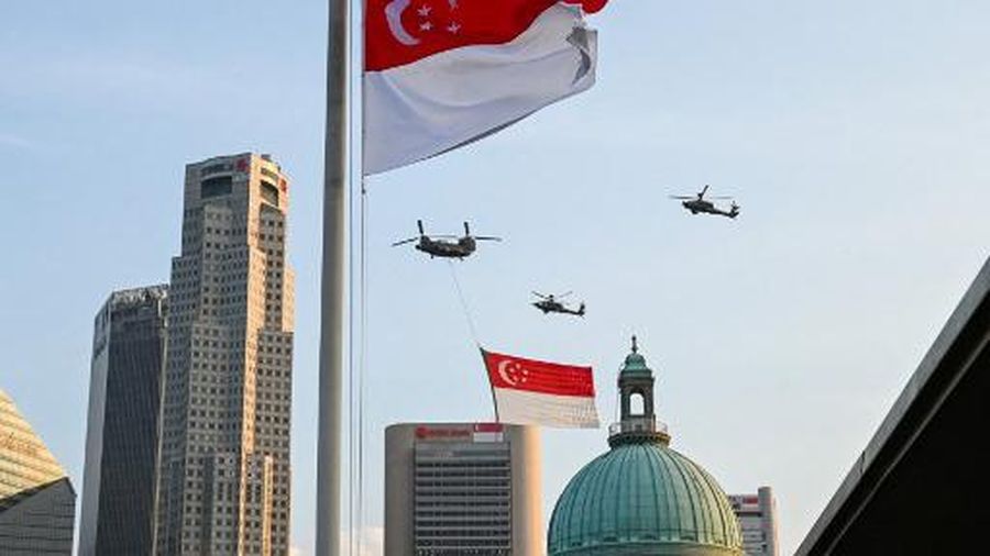 A Singapore's Air Force Chinook helicopter escorted by Apache helicopters parade with the flag of Singapore to mark the country's 57th National Day, in Singapore on August 9, 2022. (Photo by Roslan RAHMAN / AFP)