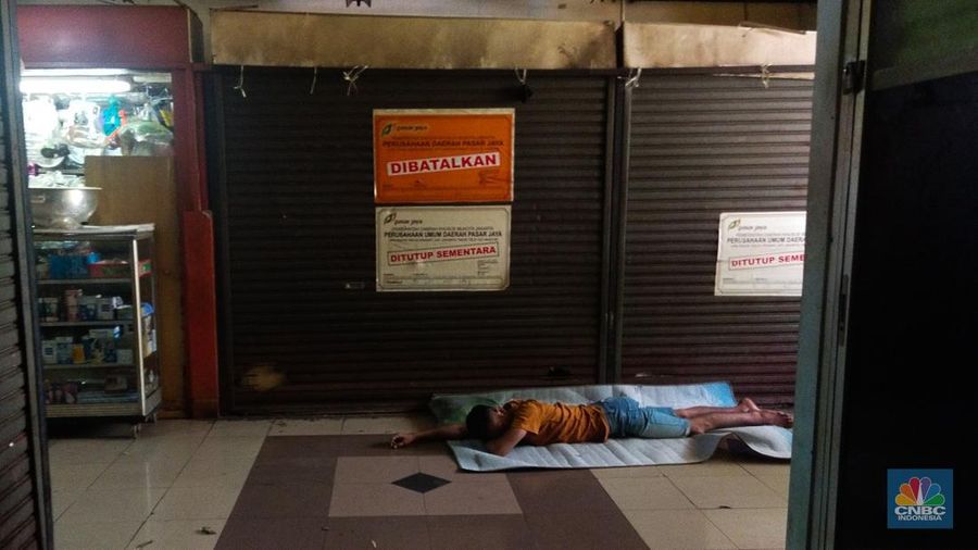 Warga beristirahat dengan memanfaatkan ruko yang terbengkalai di Pasar Induk Kramat Jati Blok 1 ACT, Jakarta, Jumat (14/7/2023). (CNBC Indonesia/Tri Susilo)