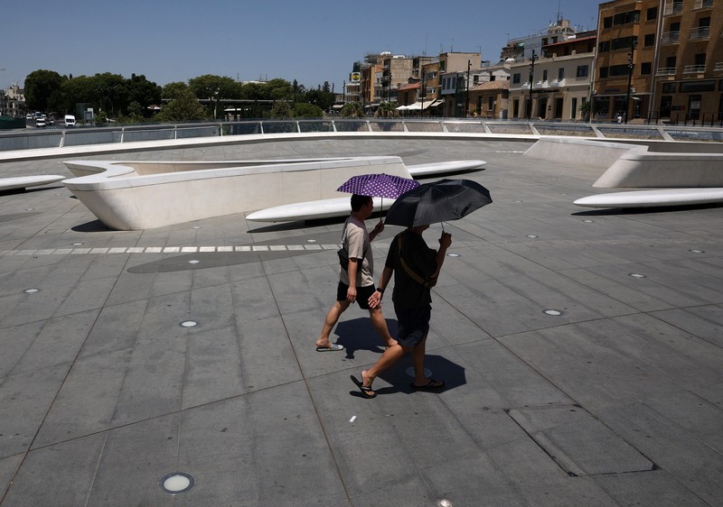 Seorang pria bernama David memeriksa ponselnya saat dia berdiri di dekat kipas angin untuk mendinginkan diri, selama gelombang panas di seluruh Italia, di Roma, 14 Juli 2023. (REUTERS/Guglielmo Mangiapane)