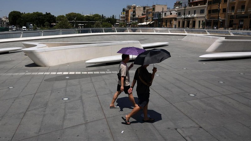 Seorang pria bernama David memeriksa ponselnya saat dia berdiri di dekat kipas angin untuk mendinginkan diri, selama gelombang panas di seluruh Italia, di Roma, 14 Juli 2023. (REUTERS/Guglielmo Mangiapane)
