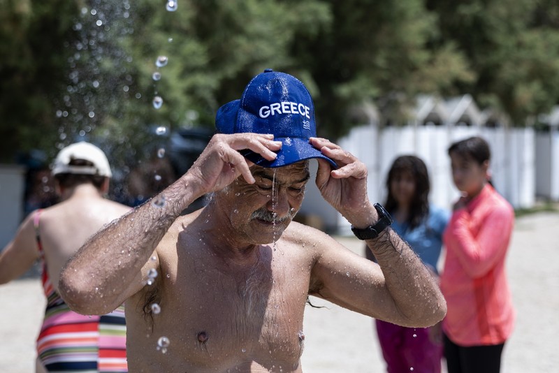 Seorang pria bernama David memeriksa ponselnya saat dia berdiri di dekat kipas angin untuk mendinginkan diri, selama gelombang panas di seluruh Italia, di Roma, 14 Juli 2023. (REUTERS/Guglielmo Mangiapane)