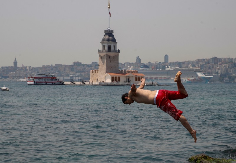 Seorang pria bernama David memeriksa ponselnya saat dia berdiri di dekat kipas angin untuk mendinginkan diri, selama gelombang panas di seluruh Italia, di Roma, 14 Juli 2023. (REUTERS/Guglielmo Mangiapane)