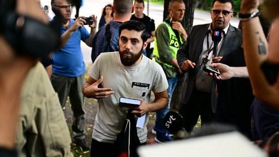 Ahmad A. (C) who has been given permission by the police for a public gathering to burn a Torah and a Bible outside the Isaeli embassy in Stockholm, Sweden, is surrounded by journalists on July 15, 2023, after he chose not to burn the books but to hold a manifestation holding a Quran in his hand. (Photo by Magnus LEJHALL / TT NEWS AGENCY / AFP) / Sweden OUT