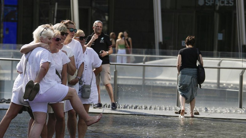 Seorang pria bernama David memeriksa ponselnya saat dia berdiri di dekat kipas angin untuk mendinginkan diri, selama gelombang panas di seluruh Italia, di Roma, 14 Juli 2023. (REUTERS/Guglielmo Mangiapane)