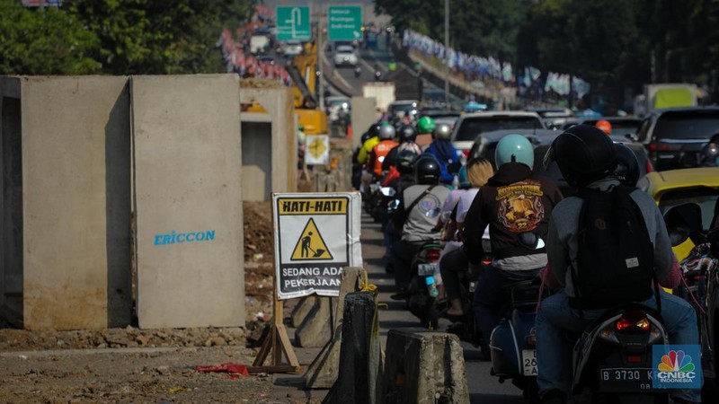 Pengendara melintas di dekat proyek pembangunan saluran air atau drainase di Jalan KH Abdullah Syafei, Jakarta, Senin (17/7/2023). (CNBC Indonesia/Faisal Rahman)