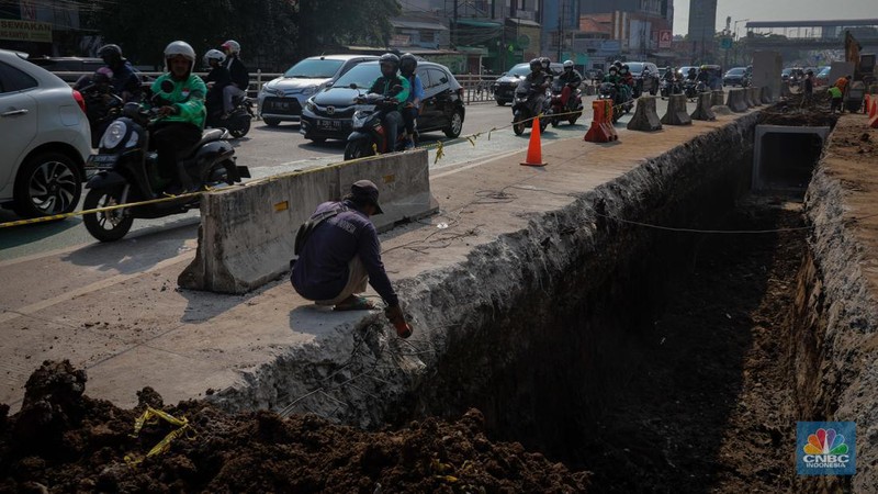 Pengendara melintas di dekat proyek pembangunan saluran air atau drainase di Jalan KH Abdullah Syafei, Jakarta, Senin (17/7/2023). (CNBC Indonesia/Faisal Rahman)