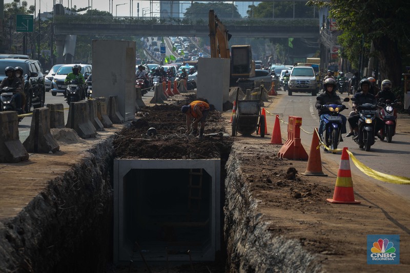 Pengendara melintas di dekat proyek pembangunan saluran air atau drainase di Jalan KH Abdullah Syafei, Jakarta, Senin (17/7/2023). Pengendara melintas di dekat proyek pembangunan saluran air atau drainase di Jalan KH Abdullah Syafei, Jakarta, Senin (17/7/2023). (CNBC Indonesia/Faisal Rahman)