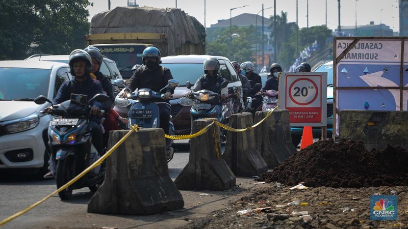 Pengendara melintas di dekat proyek pembangunan saluran air atau drainase di Jalan KH Abdullah Syafei, Jakarta, Senin (17/7/2023). (CNBC Indonesia/Faisal Rahman)
