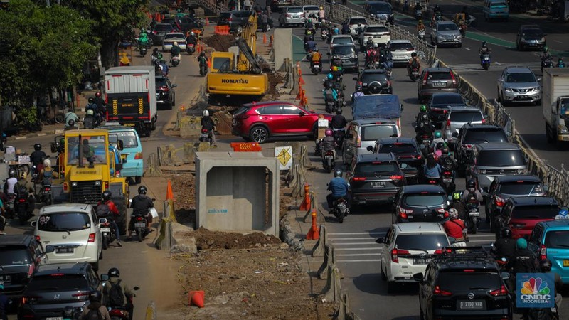 Pengendara melintas di dekat proyek pembangunan saluran air atau drainase di Jalan KH Abdullah Syafei, Jakarta, Senin (17/7/2023). (CNBC Indonesia/Faisal Rahman)