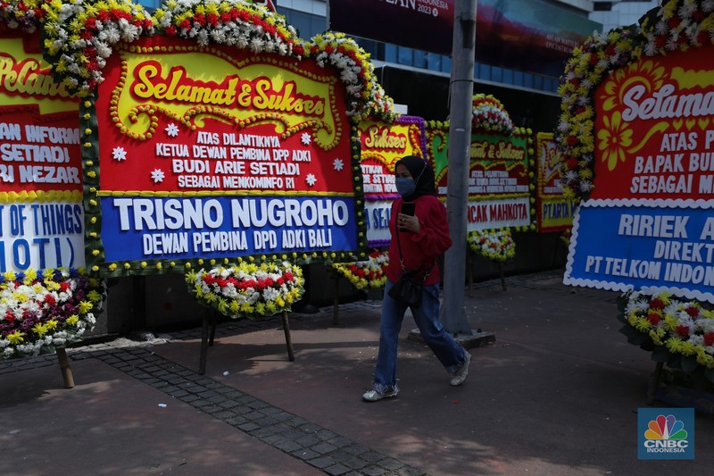 Petugas memasang karangan bunga di halaman kantor Kementerian Komunikasi dan Informatika (Kominfo) Jakarta, Senin (17/7/2023). (CNBC Indonesia/Tri Susilo)