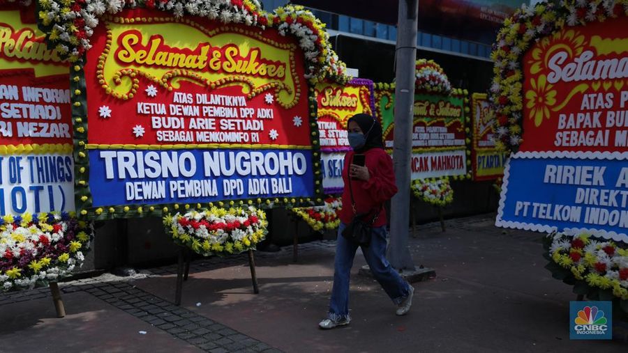 Petugas memasang karangan bunga di halaman kantor Kementerian Komunikasi dan Informatika (Kominfo) Jakarta, Senin (17/7/2023). (CNBC Indonesia/Tri Susilo)