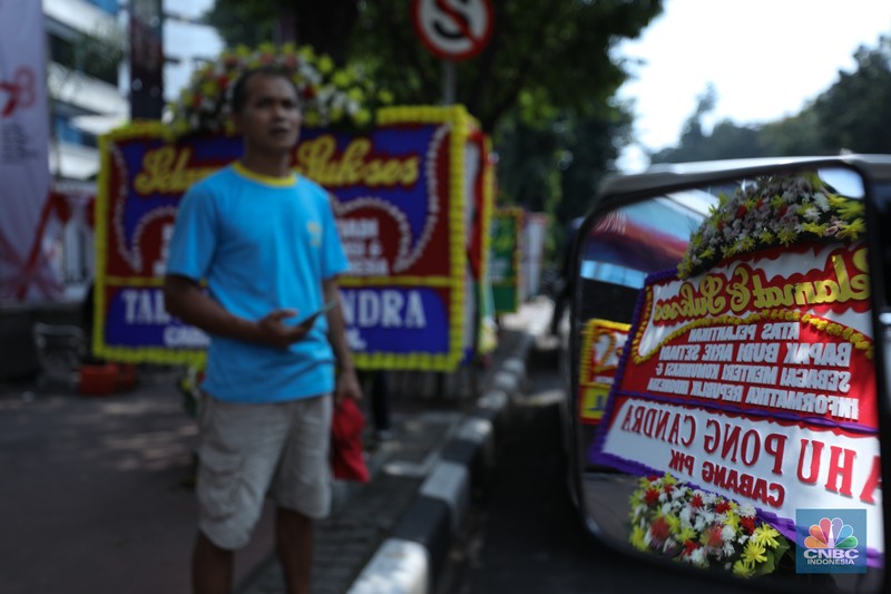 Petugas memasang karangan bunga di halaman kantor Kementerian Komunikasi dan Informatika (Kominfo) Jakarta, Senin (17/7/2023). (CNBC Indonesia/Tri Susilo)