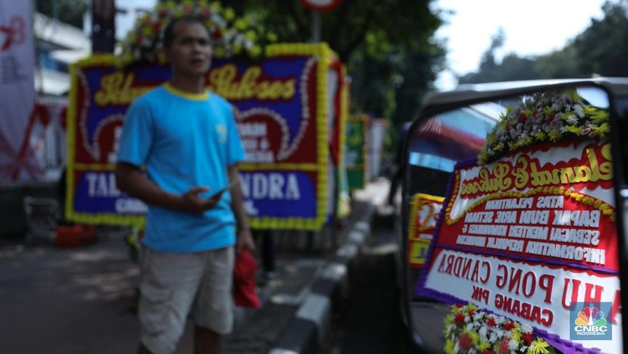 Petugas memasang karangan bunga di halaman kantor Kementerian Komunikasi dan Informatika (Kominfo) Jakarta, Senin (17/7/2023). (CNBC Indonesia/Tri Susilo)