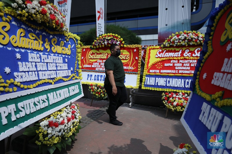 Petugas memasang karangan bunga di halaman kantor Kementerian Komunikasi dan Informatika (Kominfo) Jakarta, Senin (17/7/2023). (CNBC Indonesia/Tri Susilo)