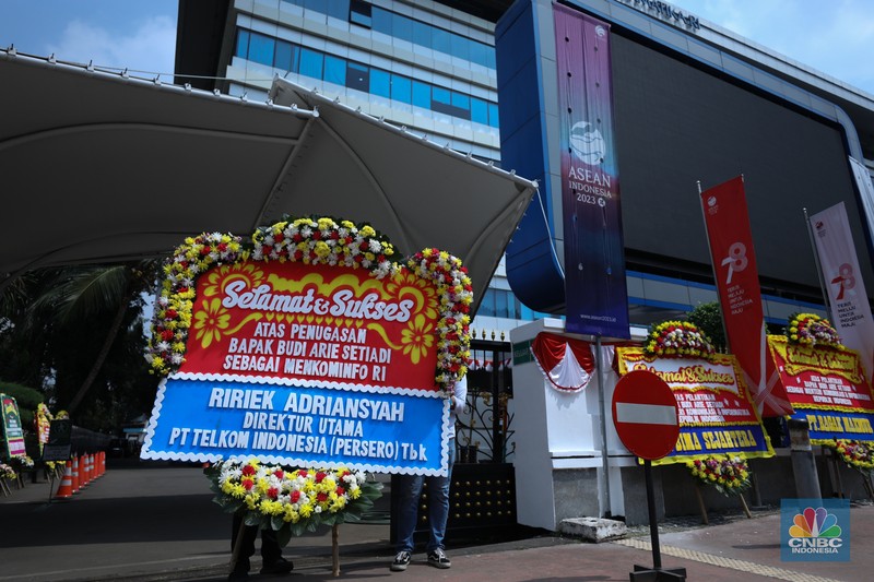 Petugas memasang karangan bunga di halaman kantor Kementerian Komunikasi dan Informatika (Kominfo) Jakarta, Senin (17/7/2023). (CNBC Indonesia/Tri Susilo)