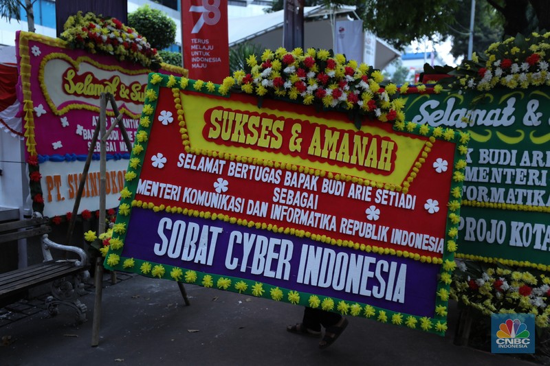 Petugas memasang karangan bunga di halaman kantor Kementerian Komunikasi dan Informatika (Kominfo) Jakarta, Senin (17/7/2023). (CNBC Indonesia/Tri Susilo)
