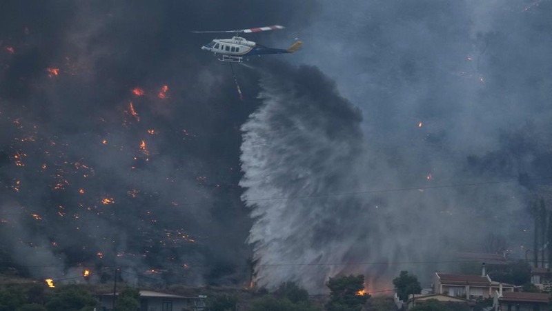 Petugas pemadam kebakaran berusaha memadamkan api yang membakar di Saronida, dekat Athena, Yunani, 17 Juli 2023. (REUTERS/Stelios Misinas)