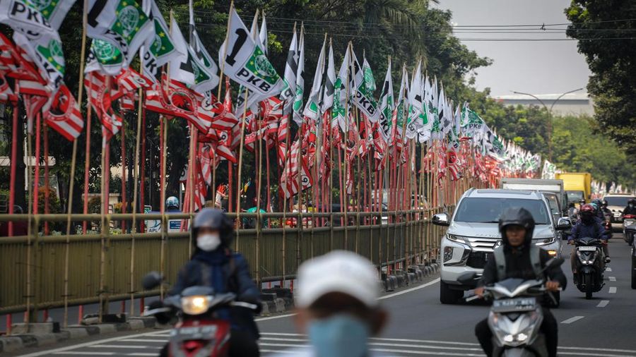 Pengendara melintas di dekat bendera parpol yang terpasang pada pembatas jalan di Jakarta, Selasa (18/7/2023).  (վ/Faisal Rahman)