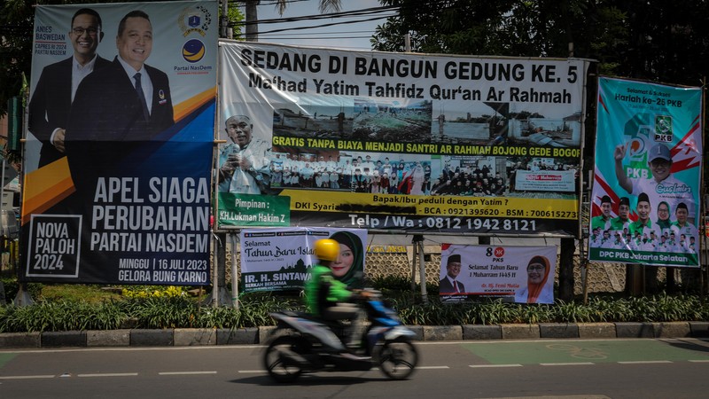 Pengendara melintas di dekat bendera parpol yang terpasang pada pembatas jalan di Jakarta, Selasa (18/7/2023).  (CNBC Indonesia/Faisal Rahman)