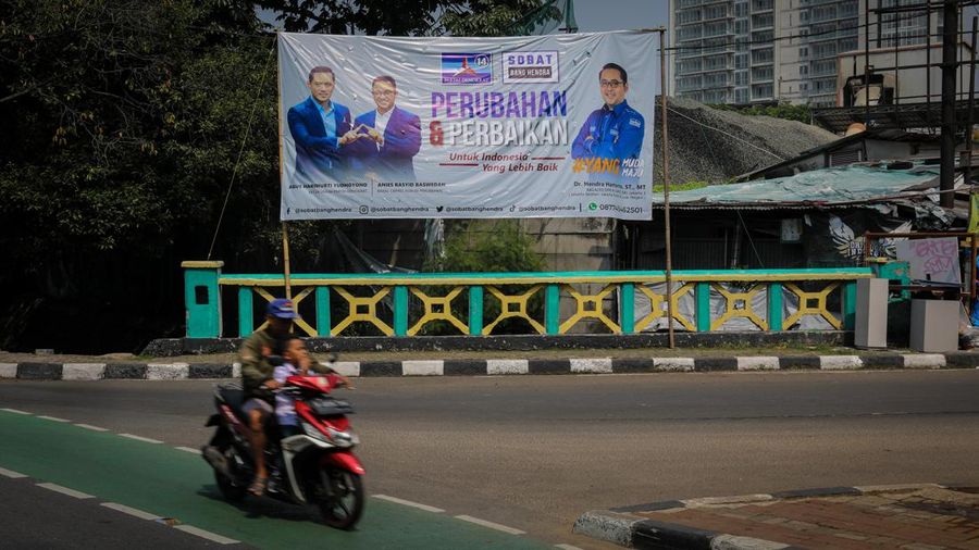 Pengendara melintas di dekat bendera parpol yang terpasang pada pembatas jalan di Jakarta, Selasa (18/7/2023).  (CNBC Indonesia/Faisal Rahman)
