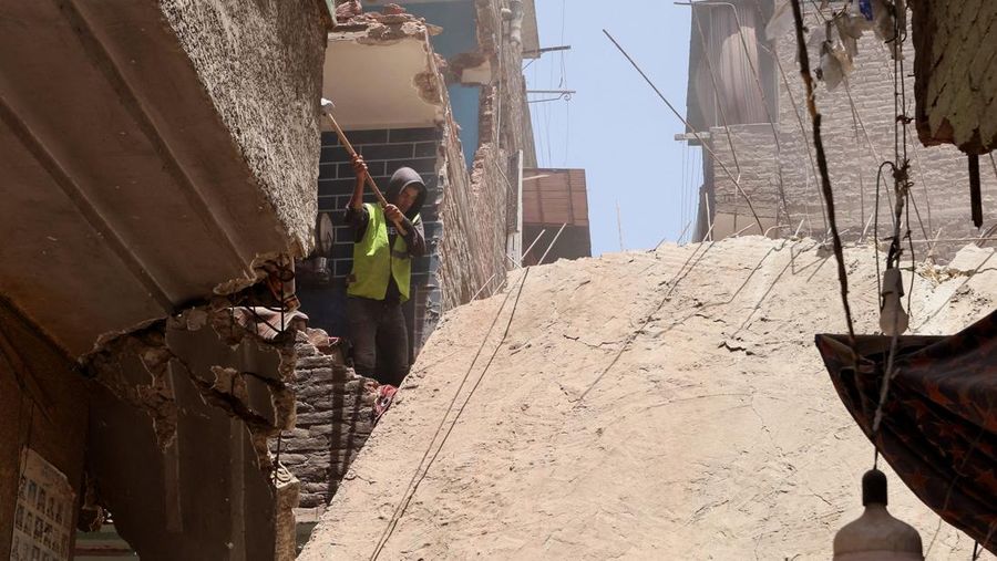Seorang pria duduk di atas puing-puing menunggu saat petugas darurat dan penyelamat Mesir mencari korban selamat di reruntuhan gedung apartemen berlantai lima yang runtuh, menyebabkan beberapa orang tewas, menurut pihak berwenang, di lingkungan Hadaeq al-Qubbah, di Kairo, Mesir, 17 Juli 2023. (REUTERS/Mohamed Abd El Ghany)