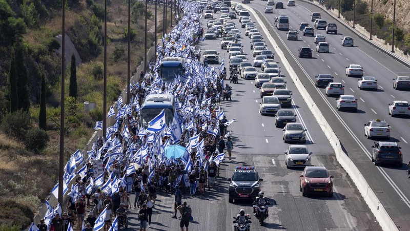 Orang-orang Israel berbaris di sepanjang Highway 1 dalam perjalanan mereka ke Yerusalem dekat Moshav Shoresh di Israel, sebagai bagian dari protes terhadap rencana pemerintah Perdana Menteri Benjamin Netanyahu untuk merombak sistem peradilan, Jumat, 21 Juli 2023 waktu setempat. (AP/Ohad Zwigenberg)