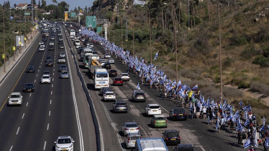 Orang-orang Israel berbaris di sepanjang Highway 1 dalam perjalanan mereka ke Yerusalem dekat Moshav Shoresh di Israel, sebagai bagian dari protes terhadap rencana pemerintah Perdana Menteri Benjamin Netanyahu untuk merombak sistem peradilan, Jumat, 21 Juli 2023 waktu setempat. (AP/Ohad Zwigenberg)