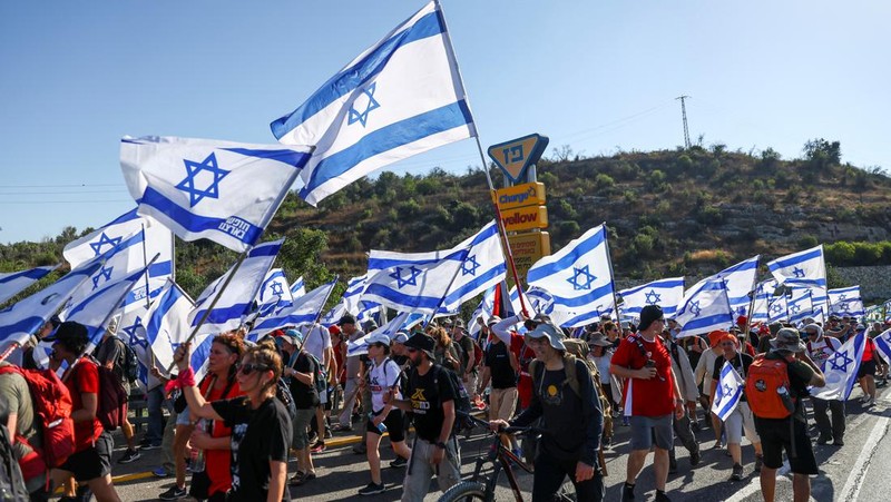 Orang-orang Israel berbaris di sepanjang Highway 1 dalam perjalanan mereka ke Yerusalem dekat Moshav Shoresh di Israel, sebagai bagian dari protes terhadap rencana pemerintah Perdana Menteri Benjamin Netanyahu untuk merombak sistem peradilan, Jumat, 21 Juli 2023 waktu setempat. (AP/Ohad Zwigenberg)