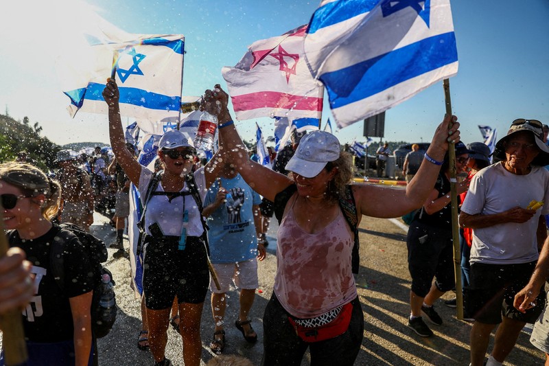 Orang-orang Israel berbaris di sepanjang Highway 1 dalam perjalanan mereka ke Yerusalem dekat Moshav Shoresh di Israel, sebagai bagian dari protes terhadap rencana pemerintah Perdana Menteri Benjamin Netanyahu untuk merombak sistem peradilan, Jumat, 21 Juli 2023 waktu setempat. (AP/Ohad Zwigenberg)