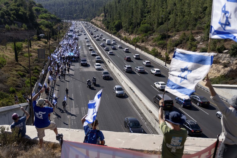 Orang-orang Israel berbaris di sepanjang Highway 1 dalam perjalanan mereka ke Yerusalem dekat Moshav Shoresh di Israel, sebagai bagian dari protes terhadap rencana pemerintah Perdana Menteri Benjamin Netanyahu untuk merombak sistem peradilan, Jumat, 21 Juli 2023 waktu setempat. (AP/Ohad Zwigenberg)