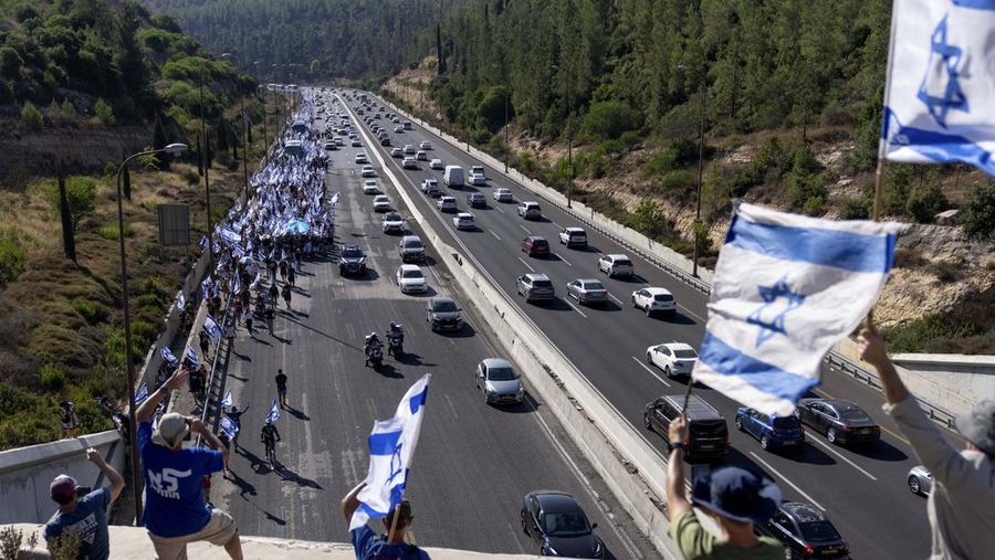 Orang-orang Israel berbaris di sepanjang Highway 1 dalam perjalanan mereka ke Yerusalem dekat Moshav Shoresh di Israel, sebagai bagian dari protes terhadap rencana pemerintah Perdana Menteri Benjamin Netanyahu untuk merombak sistem peradilan, Jumat, 21 Juli 2023 waktu setempat. (AP/Ohad Zwigenberg)